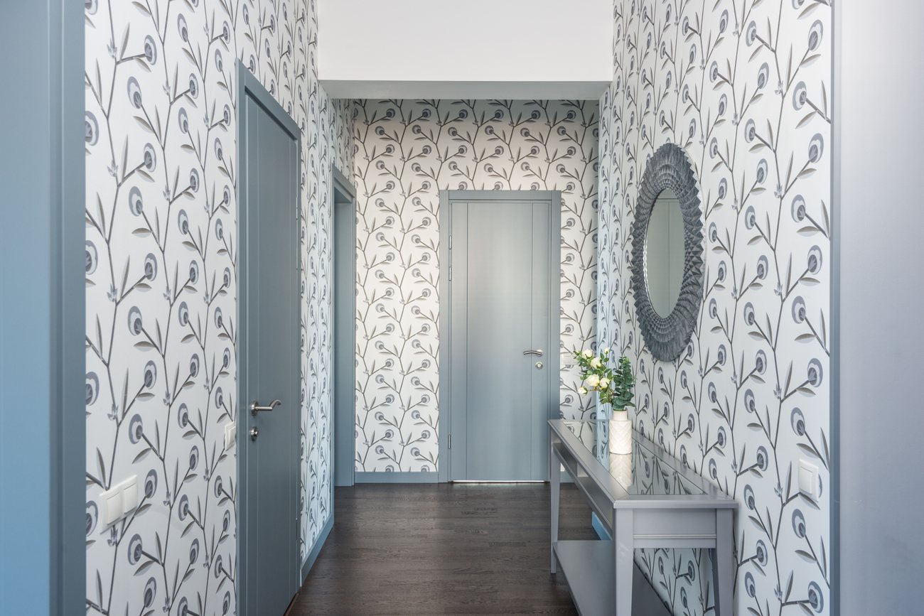 Entry hallway finished with a botanical print wallpaper, console table, and round mirror