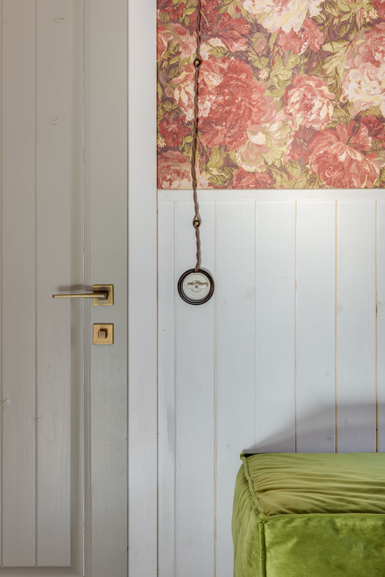 Detail view of a floral wallpaper transitioning into painted wood paneling